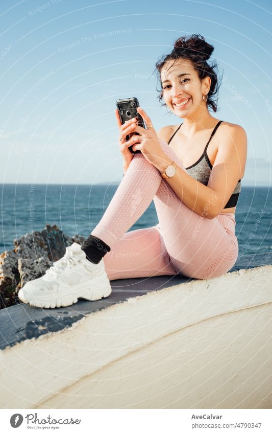Nahaufnahme einer jungen Frau, die ihr Telefon nach einem Trainingstag im Freien überprüft. Überprüfung der sozialen Medien und die Veröffentlichung neuer Bilder zu ihren Fans. Berühmte Sportler und Körper Sommer gut aussehende Konzept.