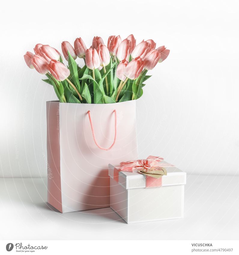Schöne rosa Tulpen Blumenstrauß in Einkaufstasche und Geschenk-Box mit Schleife auf weißem Hintergrund. schön Gruß Einstellung Geschenkverpackung Bändchen