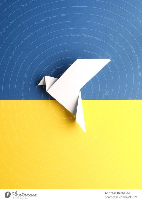 Friedenssymbol mit einer Origami-Taube auf blauem und gelbem Papier Welt Freiheit weltweit Liebe Vertrauen Hoffnung Farbe Ukraine Fahne Transformation Konzept