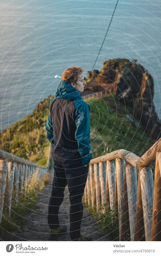 Ein Student in einer Jacke genießt die Aussicht von Cristo Rei, Camara de Lomos, Madeira, das zu Portugal gehört. Sonnenaufgang an der Atlantikküste. Die Entdeckung des europäischen Kontinents