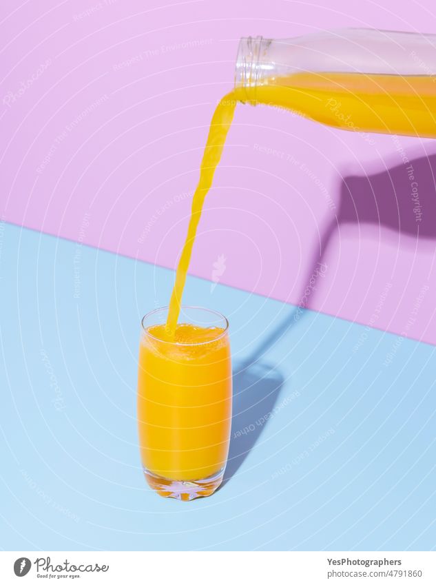 Orangensaftglas auf einem blauen Tisch. Einschenken von Orangensaft. Hintergrund Getränk Flasche Frühstück hell Zitrusfrüchte Nahaufnahme Farbe farbenfroh zyan