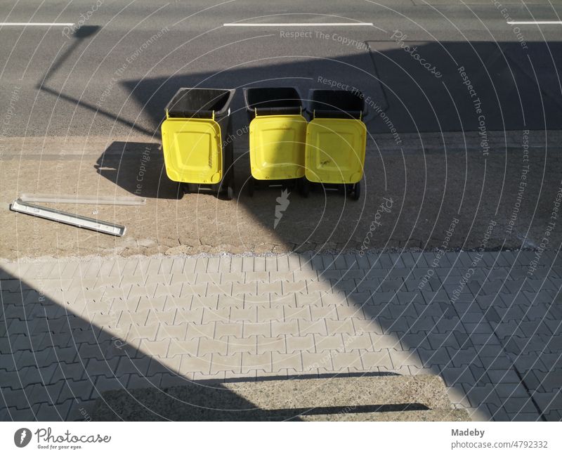 Mülltonnen für das Recycling von Verpackungen mit offenem gelben Deckel im Sonnenschein auf dem Bürgersteig in Oerlinghausen bei Bielefeld am Hermannsweg im Teutoburger Wald in Ostwestfalen-Lippe