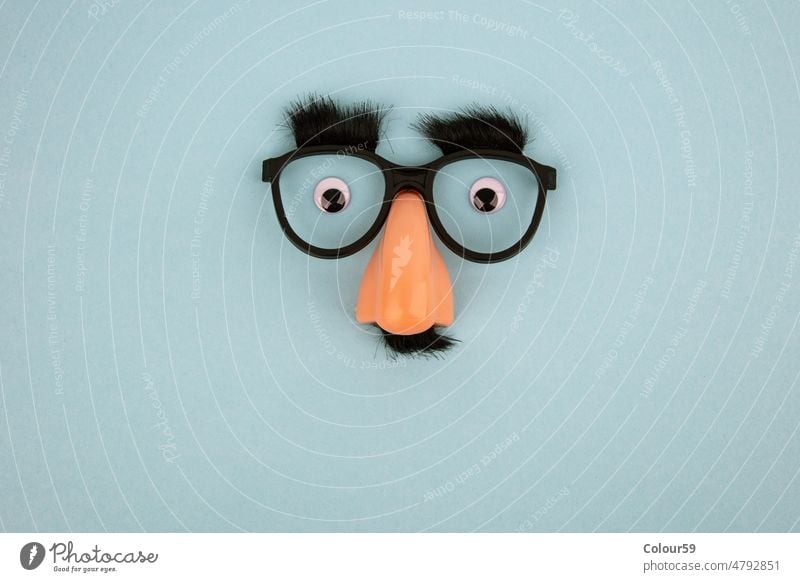 Lustige Maske mit dicken schwarzen Augenbrauen, Brille und großer Nase Mundschutz lustig Symbol Gesicht gebastelt hell-blau Hintergrund Schaffung kreativ