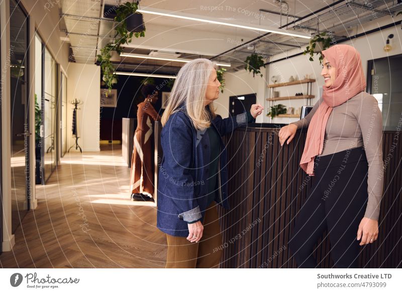 Porträt multiethnischer Geschäftsfrauen bei einem zwanglosen Treffen in einem Großraumbüro, eine muslimische Frau trägt einen Hidschab und lächelt Senior jung