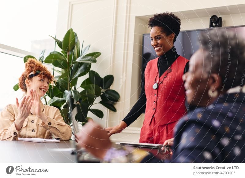 Porträt einer reifen schwarzen Geschäftsfrau in einer Besprechung mit weiblichen Kollegen, die lächeln und Beifall erhalten Frau Business Sitzung applaudieren