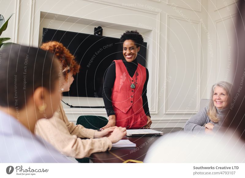 Porträt einer fröhlichen reifen schwarzen Geschäftsfrau, die weiblichen Kollegen in einem Besprechungsraum zuhört und lächelt Frau Business Sitzung heiter