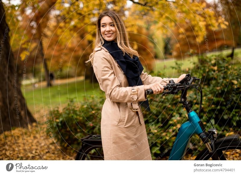Junge Frau mit Elektrofahrrad in einem herbstlichen Park aktiv Aktivität Herbst Batterie Fahrrad Biker Radfahren lässig Kaukasier Großstadt Farbe Zyklus