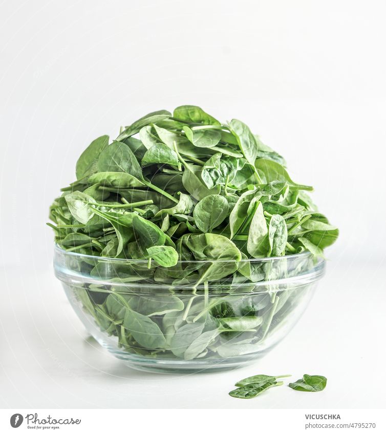 Ein Haufen roher grüner Spinatblätter in einer Glasschale auf weißem Hintergrund. Blätter Schalen & Schüsseln weißer Hintergrund Gesundheit Gemüse Bestandteil