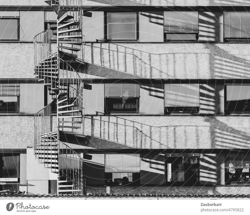 Fassade eines Bürohauses mit Feuerleitern und Schattenwurf in schwarz-weiß Struktur Jalousien Fenster bizarr Gebäude Großstadt Konstruktion urban modern trist