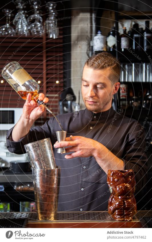 Professioneller Barkeeper gießt bei der Zubereitung eines Cocktails Alkohol in einen Jigger Mann vorbereiten Abfertigungsschalter eingießen trinken Barmann