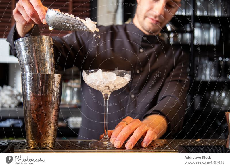 Barkeeper füllt ein Cocktailglas mit zerstoßenem Eis in einem Restaurant Mann eingießen vorbereiten trinken Glas Baggerlöffel professionell Arbeit Schüttler