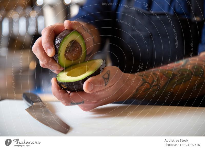 Anonymer konzentrierter Koch schneidet reife Avocado Mann Küchenchef Gemüse geschnitten kulinarisch Bestandteil Produkt Lebensmittel vorbereiten Schneidebrett