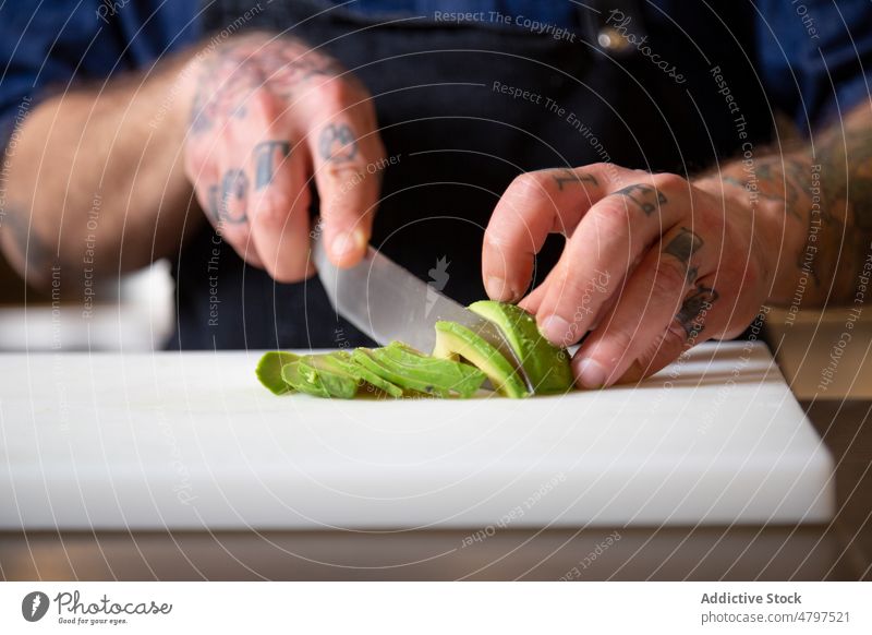 Anonymer konzentrierter Koch schneidet reife Avocado Mann Küchenchef Gemüse geschnitten kulinarisch Bestandteil Produkt Lebensmittel vorbereiten Schneidebrett