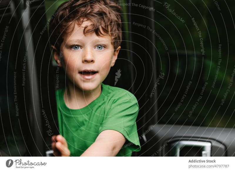 Niedlicher erstaunter Junge im Auto PKW schauen Sie Autoreise Tür öffnen Lächeln niedlich reisen Porträt neugierig Kind offen Überraschung Mund geöffnet