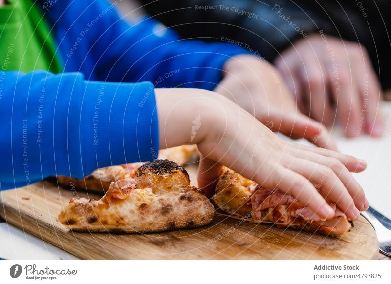 Crop-Kind isst Pizza im Restaurant essen Spielfigur Tisch Straße lecker Tradition Mittagessen Portion Junk Food Kruste Brandwunde Holz Nutzholz hölzern