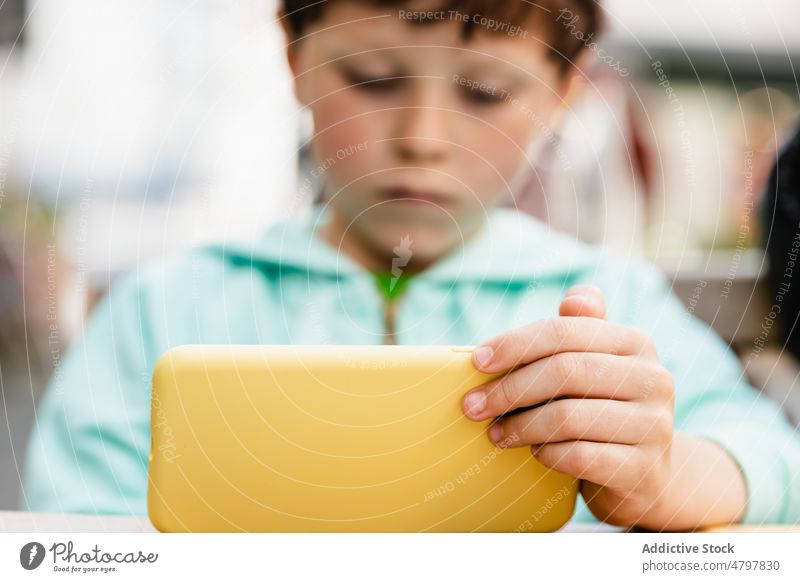 Kleiner Junge benutzt Smartphone im Restaurant benutzend zuschauen Karikatur tagsüber warten ernst online Kind Mittagessen Gerät Apparatur Tisch Video