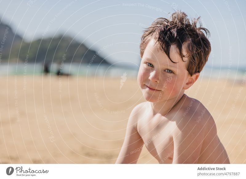Glücklicher Junge am Sandstrand schaut in die Kamera Kind Strand Sommer Küste Kindheit ruhen Zeitvertreib MEER Spaß haben positiv Lächeln Inhalt Ufer Erholung