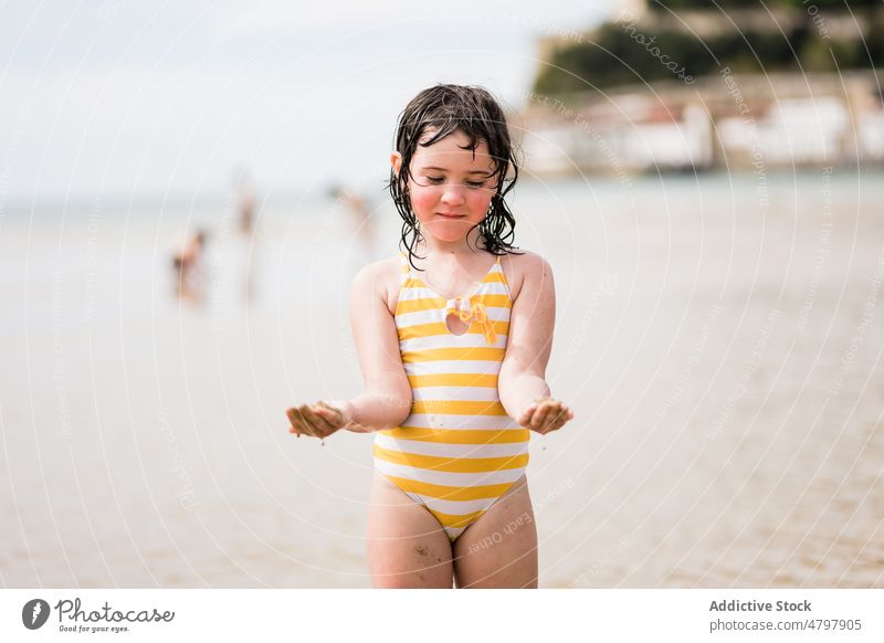 Mädchen mit nassen, sandigen Händen am Ufer Kind Strand Sommer Küste Kindheit ruhen spielerisch Wasser Erholung Freizeit spielen niedlich Sand MEER Meeresufer