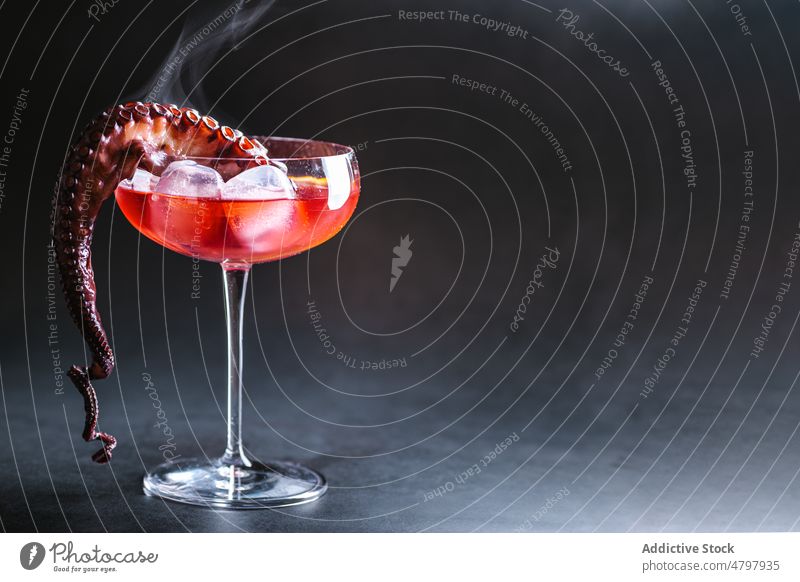 Cocktail mit Zitrone und Oktopus Weinglas Alkohol Eiswürfel trinken Aperitif Schnaps Octopus Tentakel Portion dienen Glas durchsichtig dekorieren Dekor Molluske