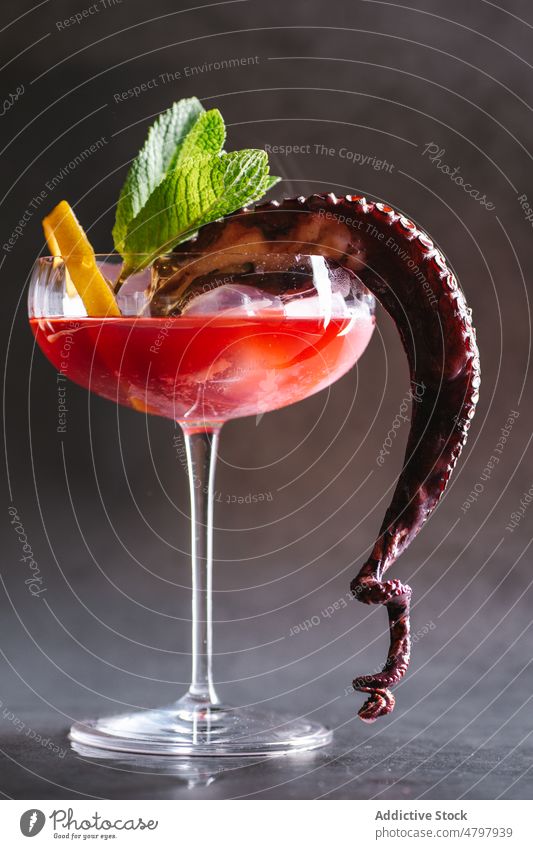 Cocktail mit Zitrone und Oktopus Weinglas Alkohol Eiswürfel trinken Aperitif Schnaps Octopus Tentakel Portion dienen Glas durchsichtig Minze dekorieren Dekor