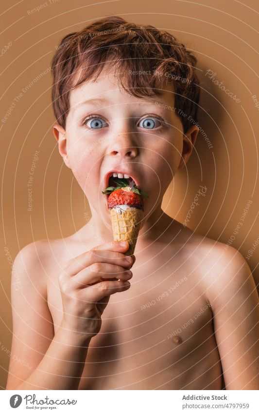 Erstaunter Junge isst Eis mit Erdbeere essen sorgenfrei Erstaunen Speiseeis Erdbeeren süß Dessert Zapfen Leckerbissen Beeren schwelgen Geschmack lecker