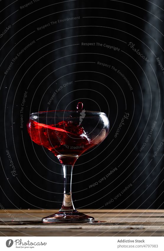 Rotwein in ein Weinglas spritzen Alkohol trinken Schnaps platschen Getränk Aperitif Geschmack verschütten liquide Kelch Glas durchsichtig Tisch Kristalle