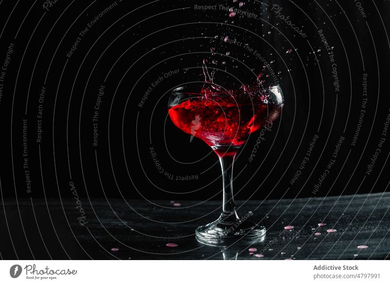 Rotwein in ein Weinglas spritzen Alkohol trinken Schnaps platschen Getränk Aperitif Geschmack verschütten liquide Kelch Glas durchsichtig Tisch Kristalle