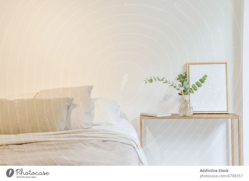 Gemütliches minimalistisches Schlafzimmer mit bequemem Bett und Holztisch Innenbereich Appartement gemütlich Kopfkissen Dekor sehr wenige Design wohnbedingt