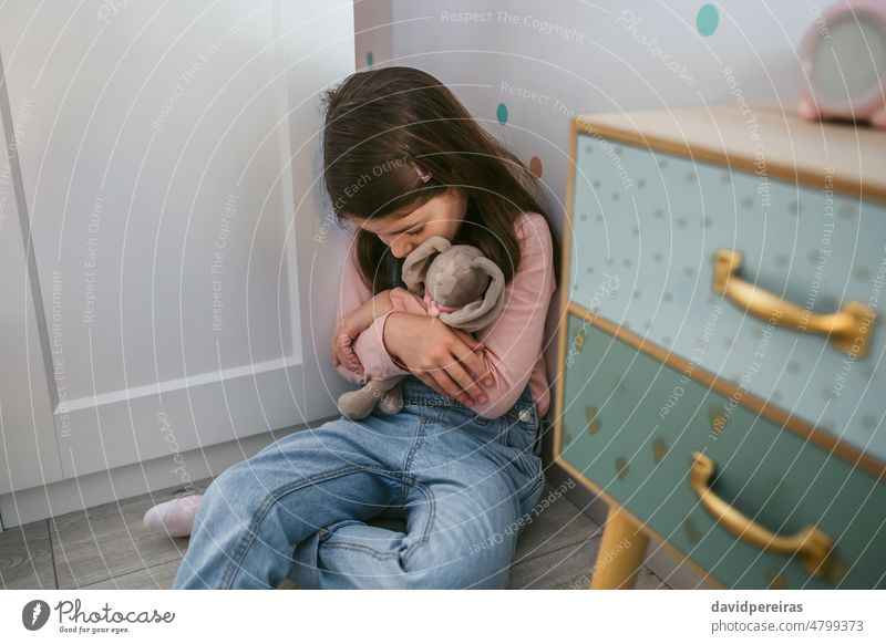 Unglückliches Mädchen umarmt Stofftier auf dem Boden sitzend unglücklich wenig traurig Umarmung gefüllt Spielzeug Sitzen Angst psychische Gesundheit deprimiert