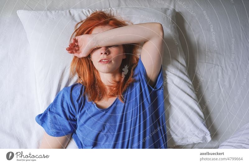 Frau, die mit Migräne und Lichtempfindlichkeit im Bett liegt und ihre Augen bedeckt Lügen Empfindlichkeit deckend müde lustlos Person Deckung jung Schlafmütze