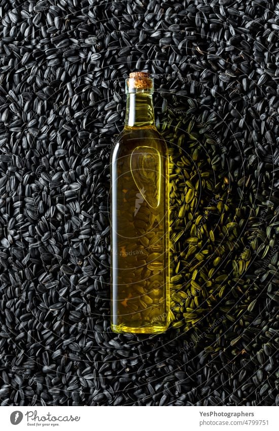 Ölflasche auf einem Haufen schwarzer Sonnenblumenkerne, Ansicht von oben. Ackerbau Hintergrund Flasche Müsli Nahaufnahme Farbe Essen zubereiten Textfreiraum