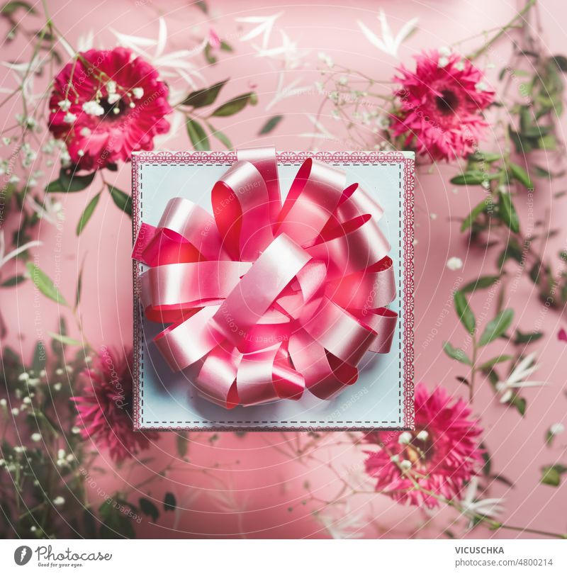 Geschenkkarton mit rosa Schleife auf floralem Hintergrund mit rosa und weißen Blumen Geschenkverpackung Bändchen geblümt zu feiern Gruß schön präsentieren