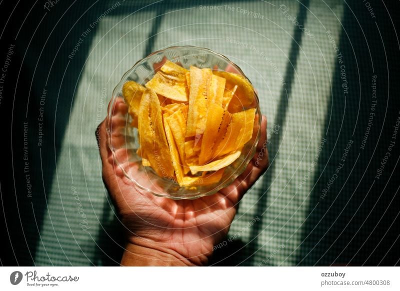 Hand mit Bananenchips auf der Schale Beteiligung Nahaufnahme Chip Snack gelb gebraten Scheibe Hintergrund trocknen knackig Gesundheit Bestandteil Vegetarier