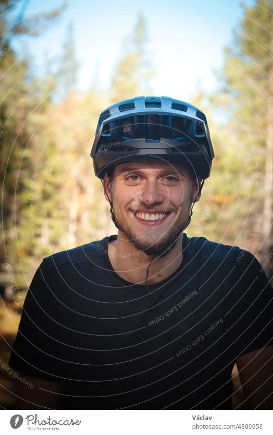 Freizeitradler lächelt zufrieden nach einer anspruchsvollen Strecke im Schlamm. Unverfälschtes Porträt eines jungen Sportlers mit einem echten Lächeln und Schlamm im Gesicht
