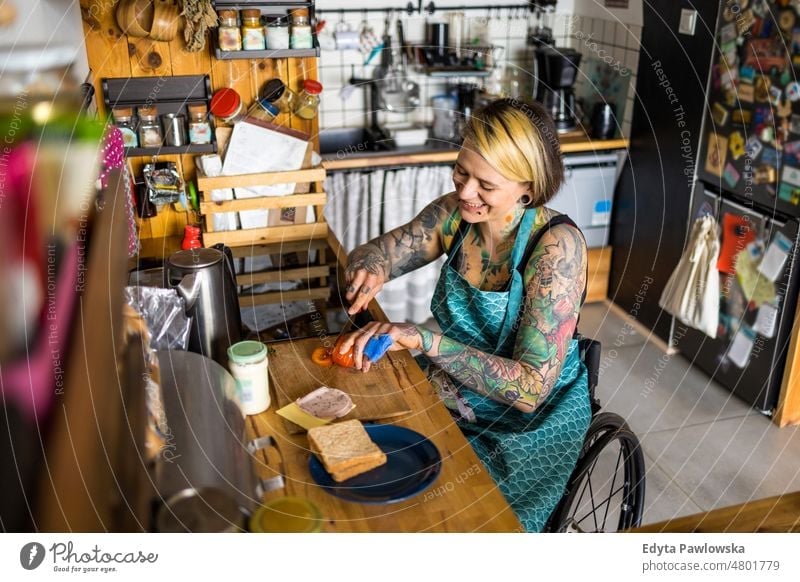 Frau im Rollstuhl bei der Zubereitung von Speisen in der Küche zu Hause häusliches Leben Selbstvertrauen im Innenbereich heimwärts Menschen jung Erwachsener