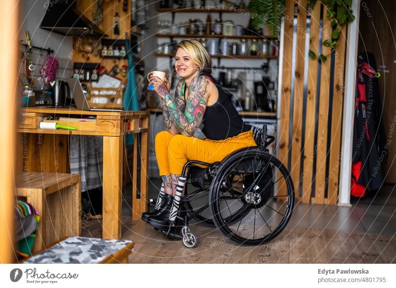 Porträt einer jungen tätowierten Frau in einem Rollstuhl zu Hause häusliches Leben Selbstvertrauen im Innenbereich heimwärts Menschen Erwachsener lässig