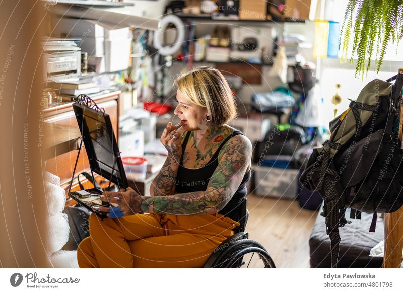 Junge Frau im Rollstuhl beim Schminken zu Hause häusliches Leben Selbstvertrauen im Innenbereich heimwärts Menschen jung Erwachsener lässig Kaukasier attraktiv