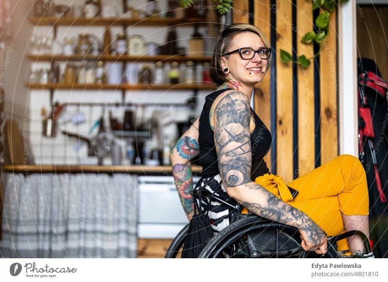 Porträt einer jungen tätowierten Frau in einem Rollstuhl zu Hause häusliches Leben Selbstvertrauen im Innenbereich heimwärts Menschen Erwachsener lässig