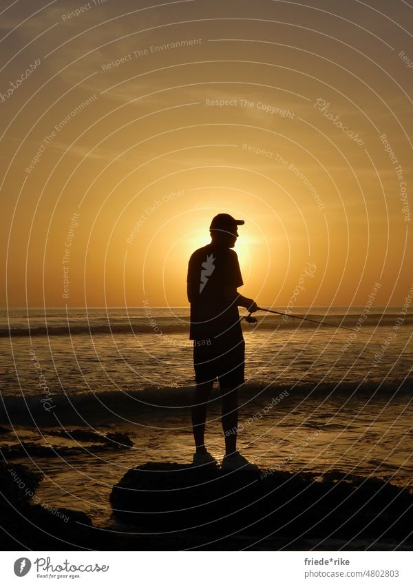 Mann mit Angel am Meer vor Sonnenuntergang Angeln Angelrute Abendstimmung Freiheit Sommerurlaub Licht Abenddämmerung Dämmerung Horizont Farbfoto Tourismus