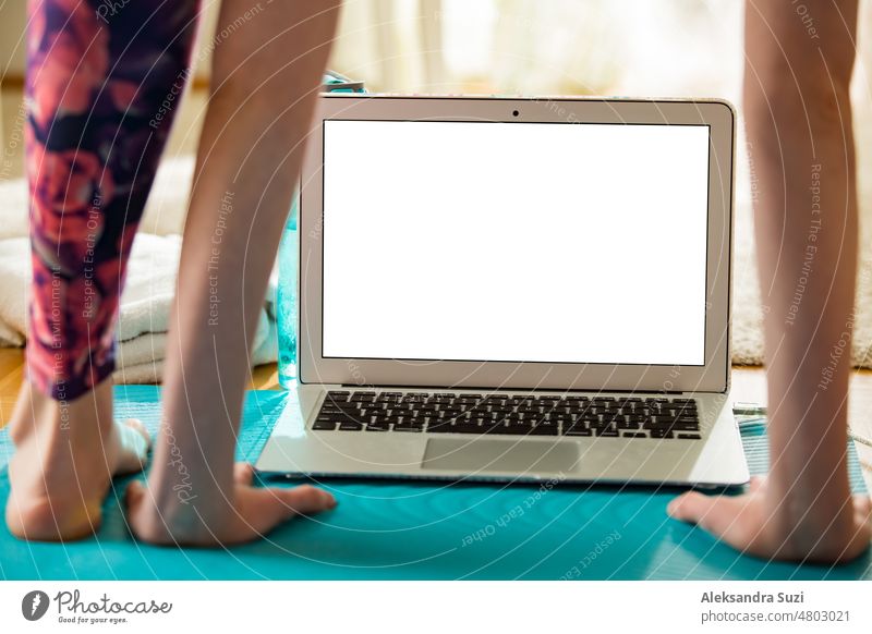 Frau, die einen Laptop benutzt und auf einer Yogamatte zu Hause trainiert. Entfernte Arbeit. Gesunder Lebensstil und Social Media Konzept. Weißer leerer Bildschirm. Gesunde Lebensweise und soziale Medien. Nahaufnahme eines leeren weißen Bildschirms.