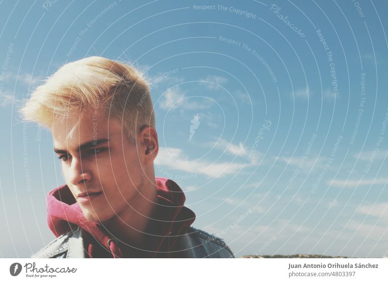 Closeup Porträt eines hübschen und attraktiven blonden Jungen mit Himmel Hintergrund Teenager gutaussehend Mann Typ ein Mann Nahaufnahme trendy Mode modisch