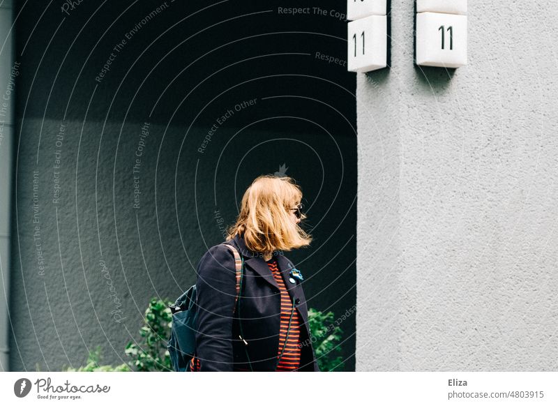 [hansa BER 2022]  Eine Frau mit mittellangen blonden Haaren unter Hausnummer 11 mittellanges Haar Nummer Wand Wohnhaus blondes Haar abgewandt Oberkörper