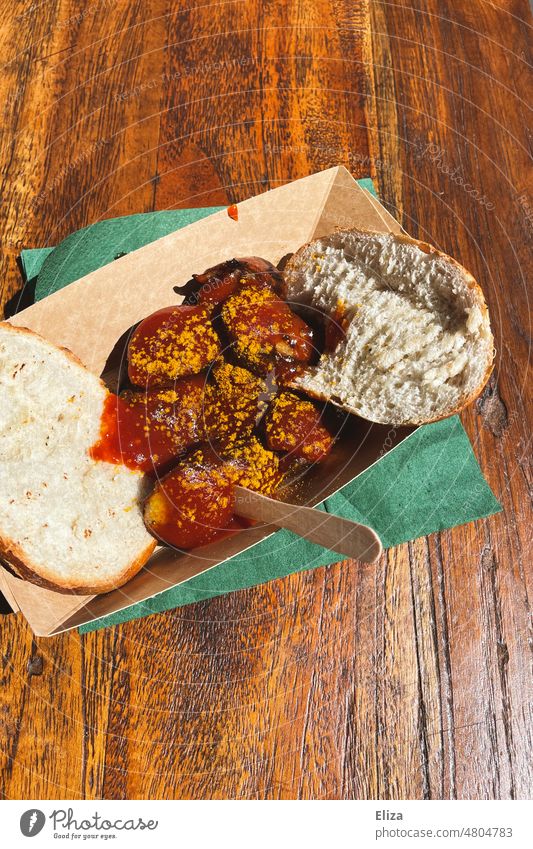 Currywurst mit Brötchen in einem Pappteller Imbiss Fastfood lecker Fleisch rot Semmel Essen Mittagessen Soße ungesund Snack Mahlzeit