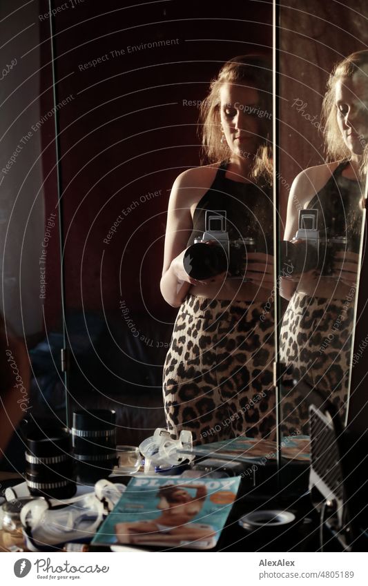 Junge Frau steht mit analogen Mittelformat- Kamera vorm Spiegel und macht ein analoges Selfie junge Frau schön feminin weiblich schlank Leoprint Identität