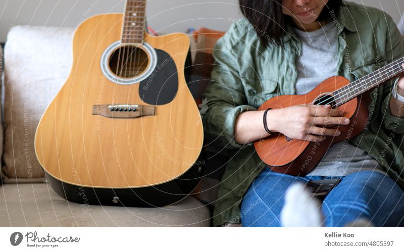 Asiatisches Mädchen spielt Ukulele Gitarre asiatisch asiatische Frau Musiker Musikinstrument Gitarren heimwärts Sofa Saite Wohnzimmer Musikerin Musikinstrumente