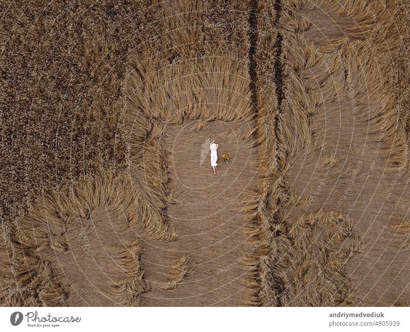 Luftaufnahme einer hübschen jungen Frau, die die Natur genießt. Mädchen im weißen Kleid liegt im Weizenfeld. Menschen, Reisen, Freiheit Konzept. Feld Model
