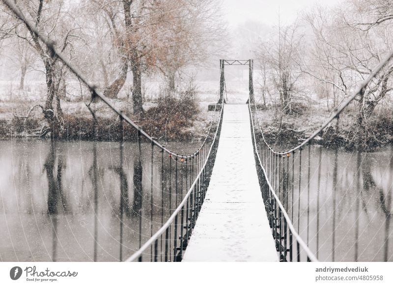 Fußgänger-Hängebrücke aus Stahl und Holz über den Fluss, Winter Brücke Landschaft Weg erhängen Wald Steg reisen Natur Ansicht hölzern hängend Park Schnee