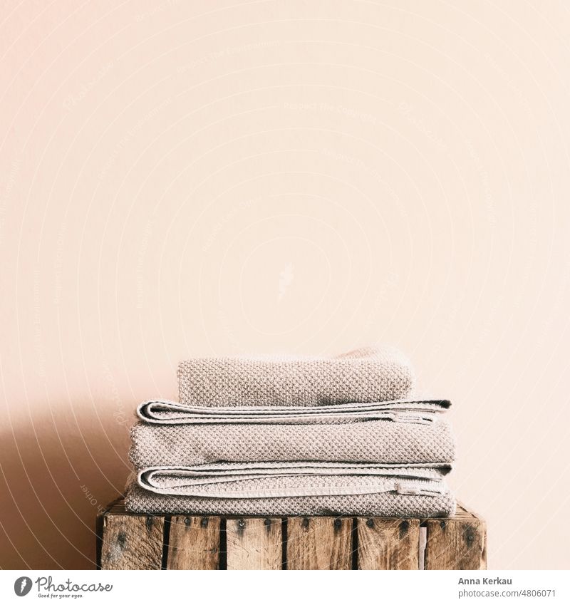 Gefaltete Handtücher auf Holzkiste vor einer hellen Wand gefaltet zusammengelegt Haushaltsführung Ordnung Häusliches Leben frische Wäsche ordnungsliebend