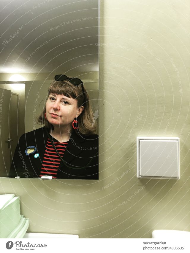 [hansa BER 2022] Prüfend den Schalter umlegen WC Blick prüfend Spiegelbild Bad Ohrringe Frau lächeln Wand Innenaufnahme Innenraum spiegelverkehrt Gesicht