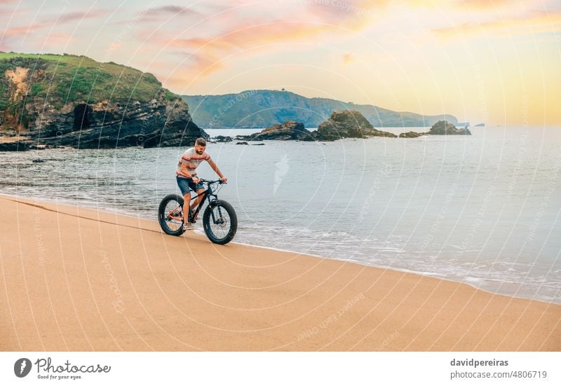 Junger Mann fährt auf einem Fatbike am Strand jung Reiten Meeresufer Textfreiraum Lächeln Landschaft Person Sport Fahrrad Lifestyle MEER Fett grün aktiv